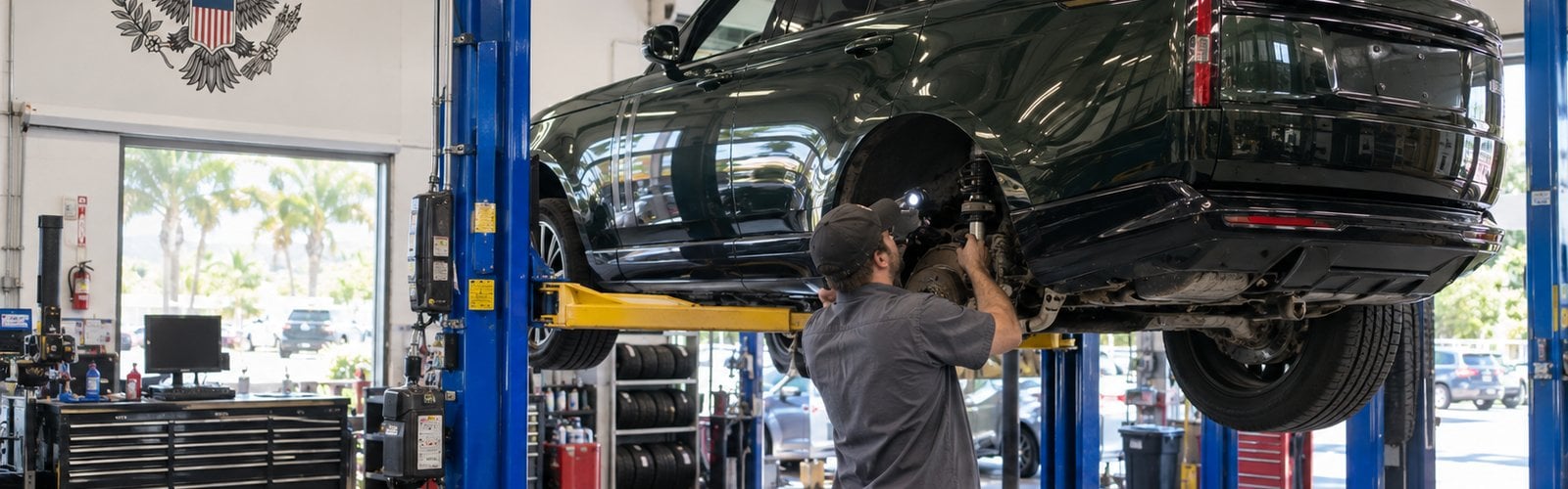 Technician inspecting the rear air suspension on a Range Rover raised on a lift at Presidential Auto Sales & Service in Delray Beach, FL